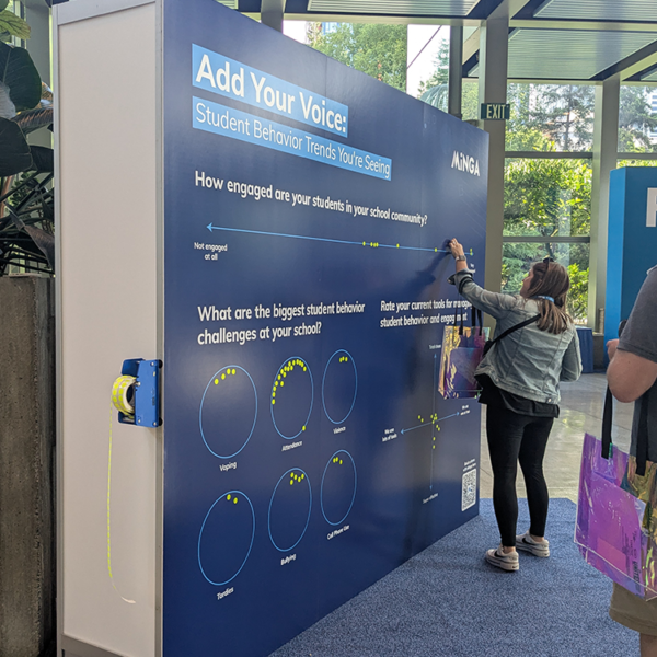An educator adds her sticker to Minga's Engagement Wall at the UNITED 2025 Conference in Seattle.