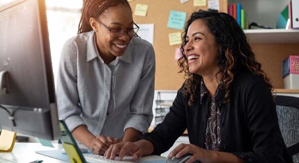 Two teachers laughing and smiling at a computer