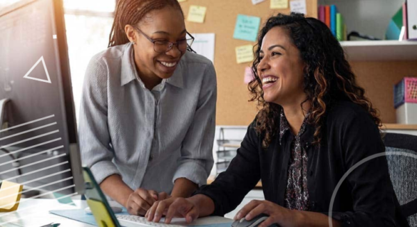Two teachers laughing and smiling at a computer
