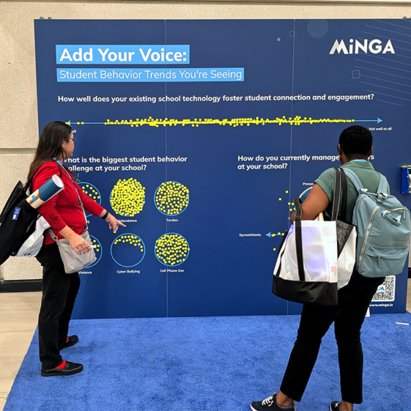 Two educators review Minga's Engagement Wall at FETC 2026, sharing views on student behavior trends.
